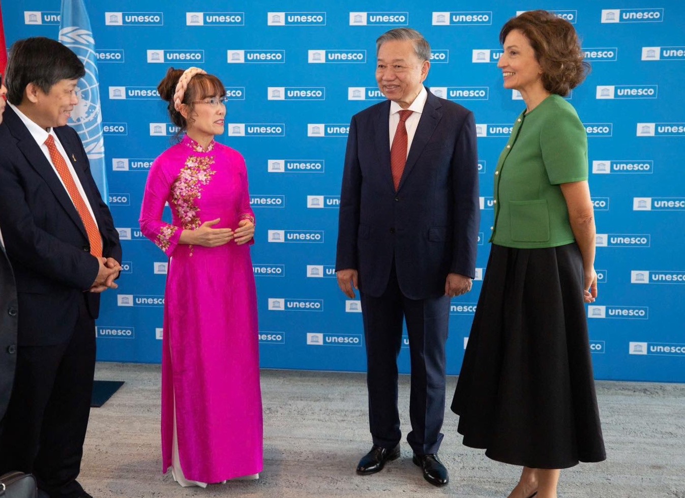 A group of people standing in front of a blue wallDescription automatically generated