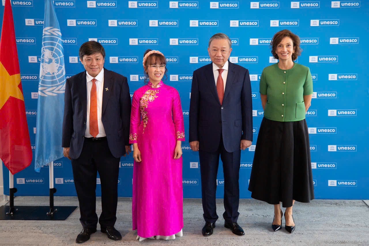 A group of people standing in front of a blue backgroundDescription automatically generated
