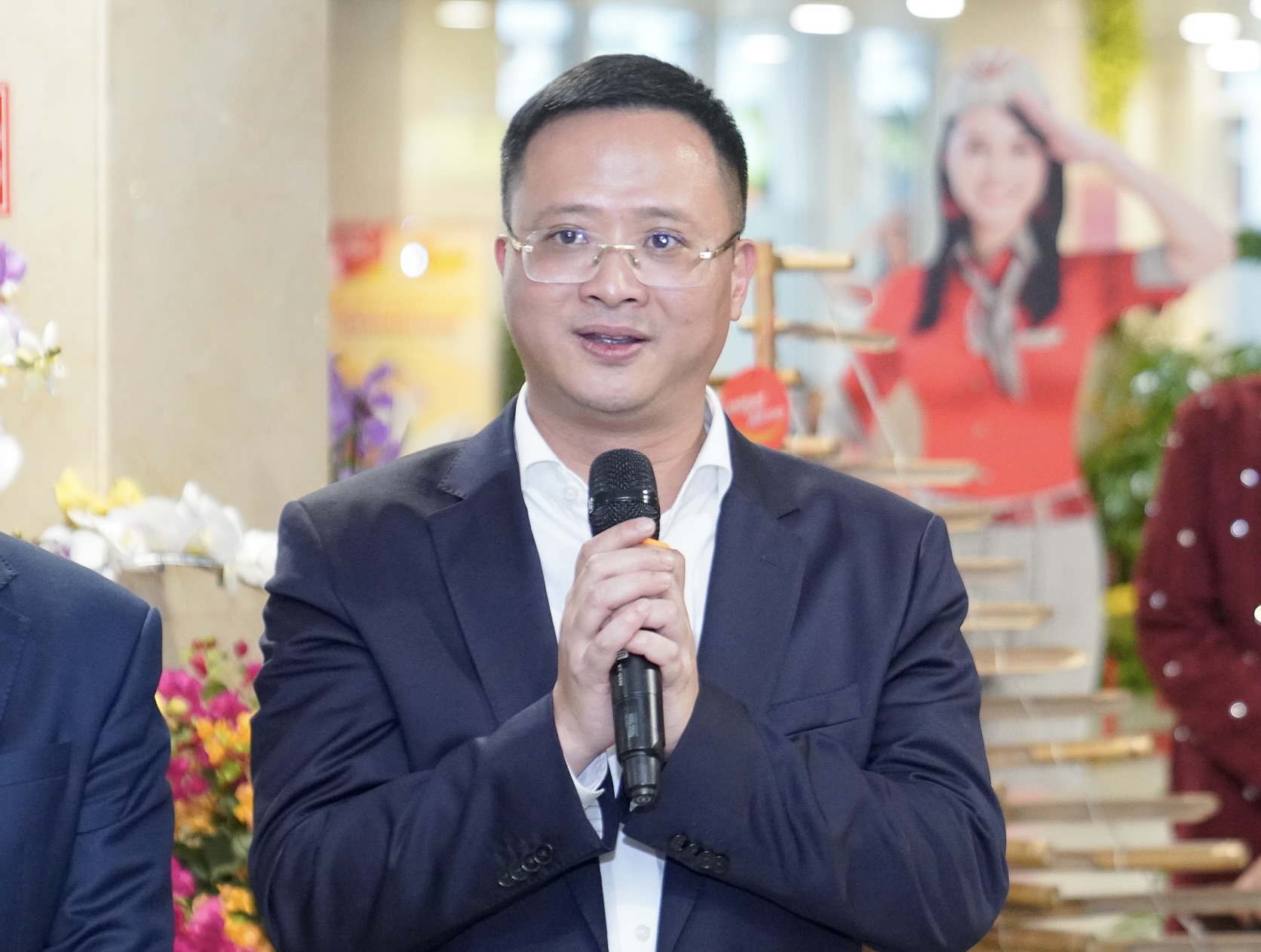 A person in a suit holding a microphoneDescription automatically generated