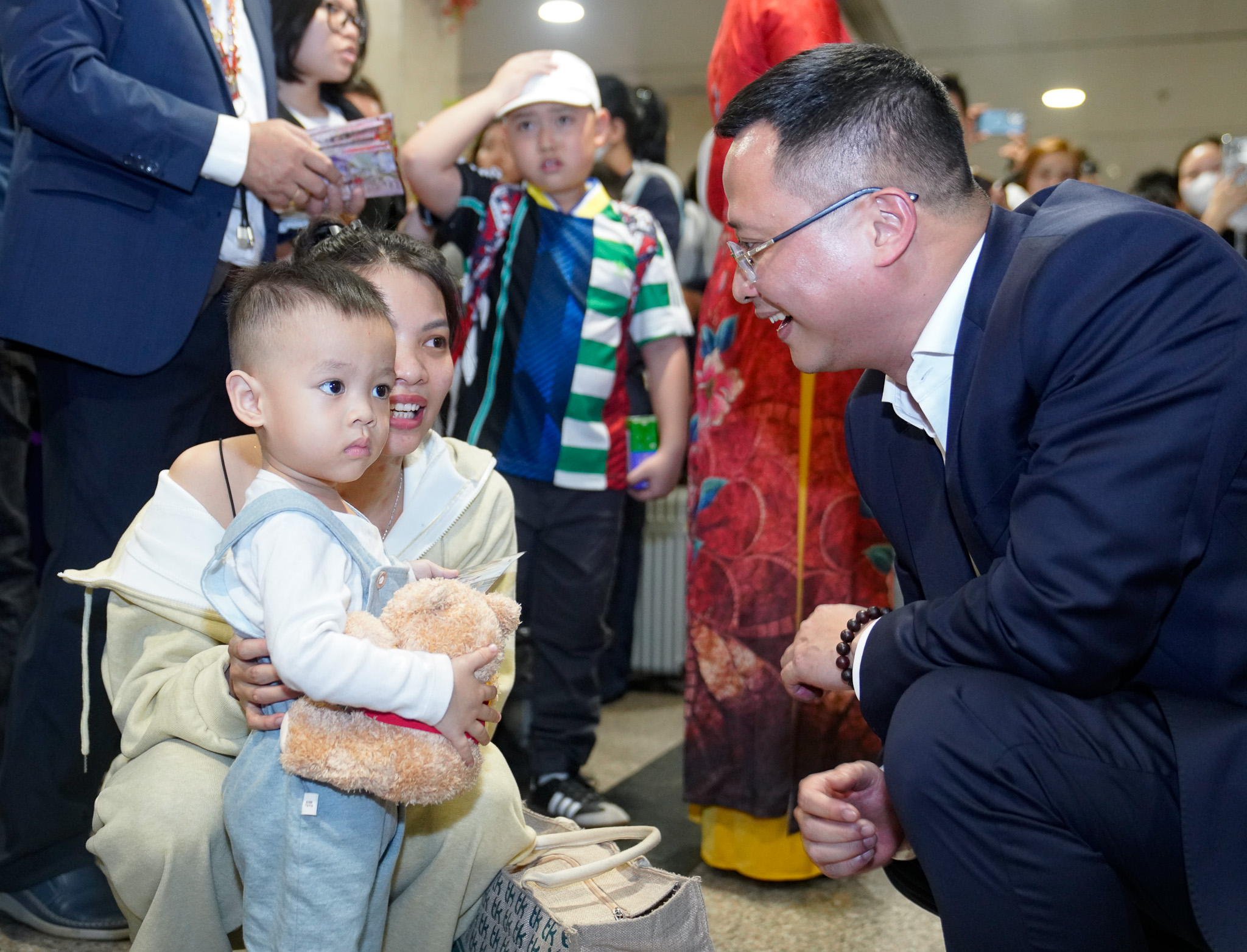 A person in a suit holding a babyDescription automatically generated