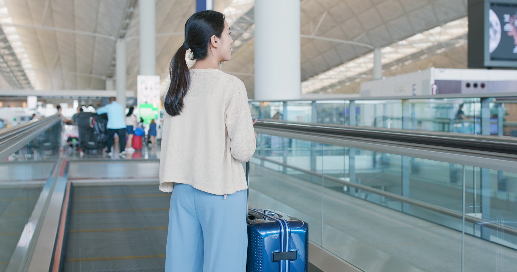 A female passenger checking flight information on an electronic departure board at the airport